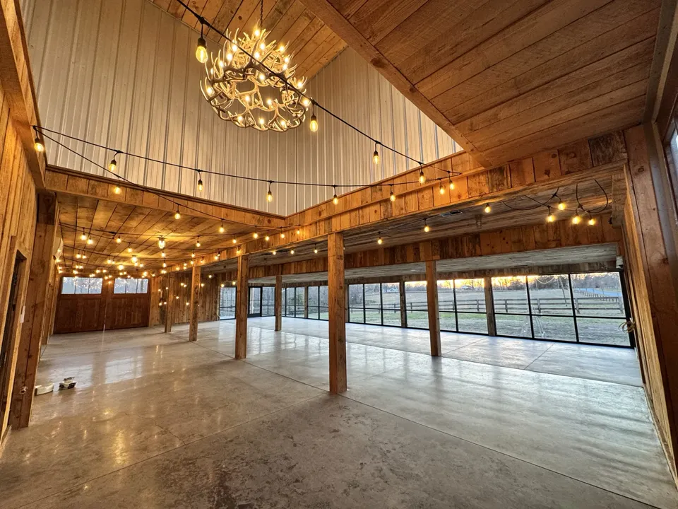 The barn interior with wood beams, chandeliers and string lights