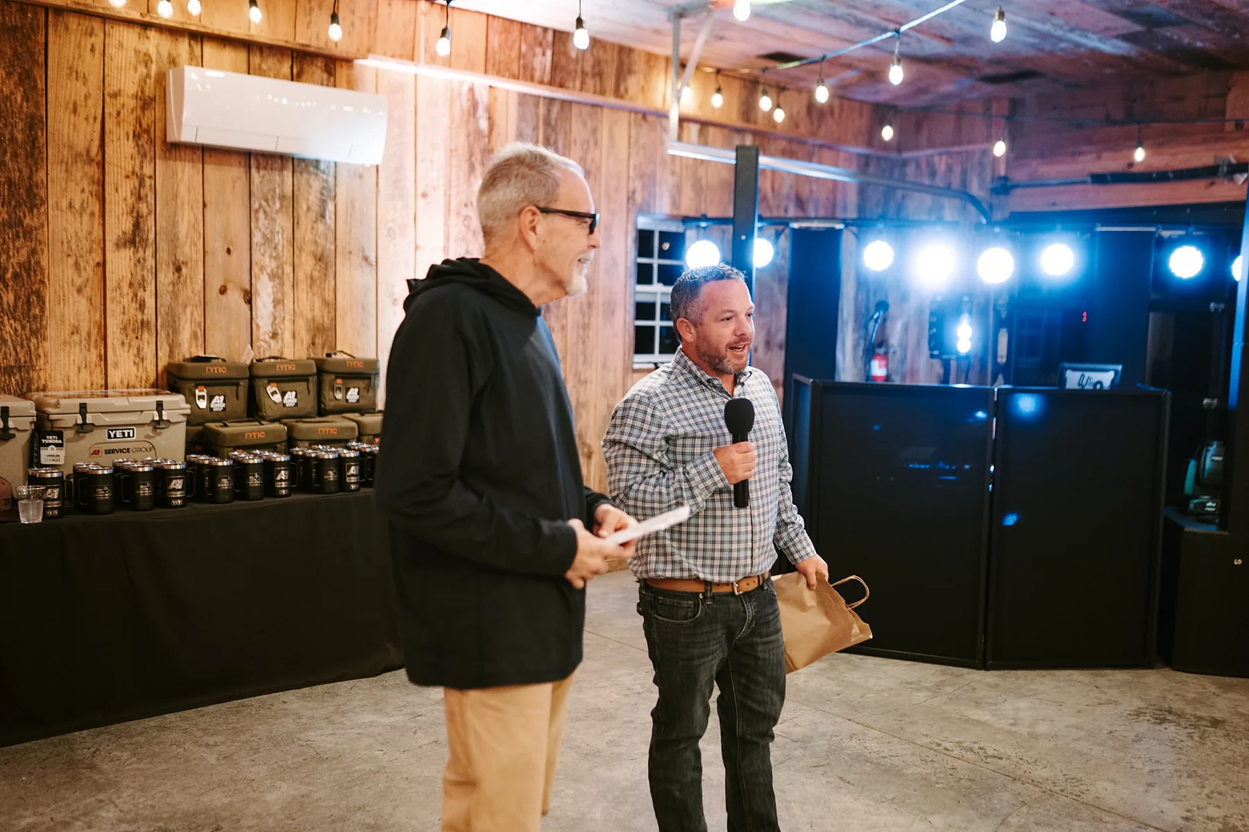 A host with a microphone presenting awards during a company event inside the barn