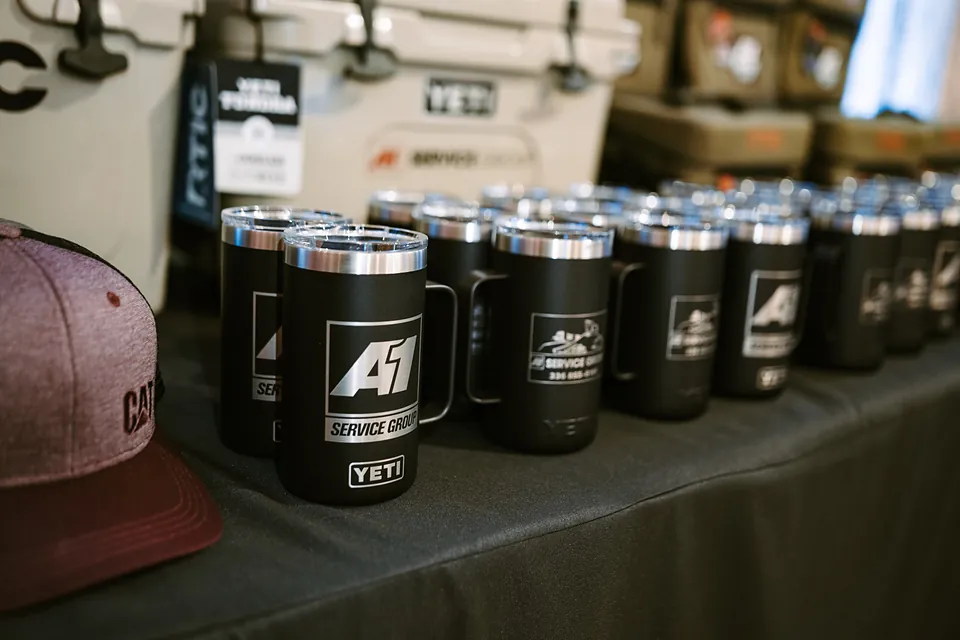 Company-branded mugs and coolers on a gift table