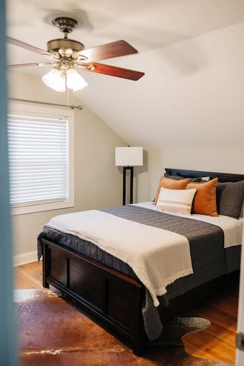 A double bed in a room with hardwood floors and a ceiling fan