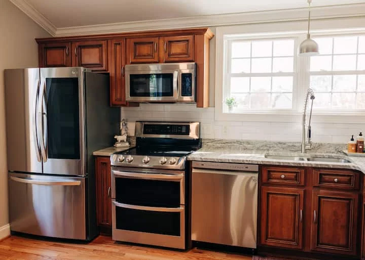 Guest-house kitchen with wood cabinets, a refrigerator, stove, microwave, and sink