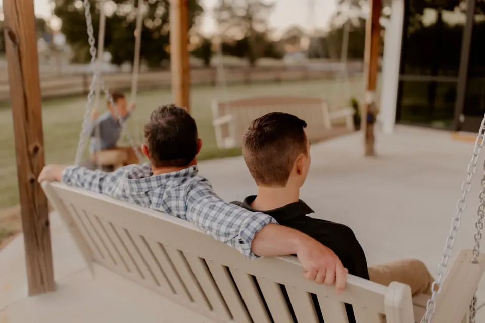 Two guests seated on a wooden swing inside the silo looking out over the pasture at dusk